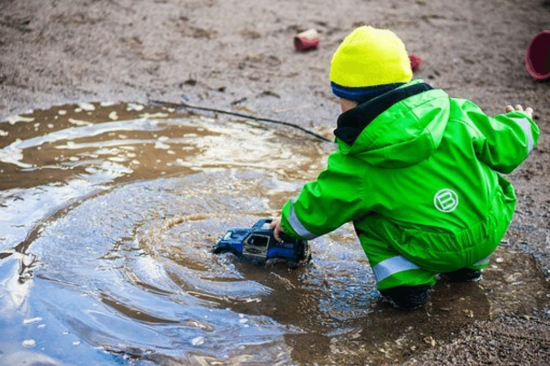 young child playing with a toy car in a puddle of water